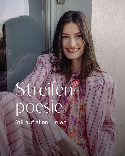 Eine Frau in einem rosa gestreiften Anzug mit geblümter Bluse lächelt, während sie am Fenster sitzt. Der Text lautet: "Streifen poesie, Stil auf allen Linien.