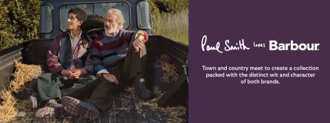 Zwei Männer sitzen in bunten Pullovern und Jacken auf der Ladefläche eines mit Heu gefüllten Pickups. Der Text lautet: "Paul Smith liebt Barbour. Stadt und Land treffen aufeinander, um eine Kollektion zu kreieren, die den ausgeprägten Witz und Charakter beider Marken in sich trägt.